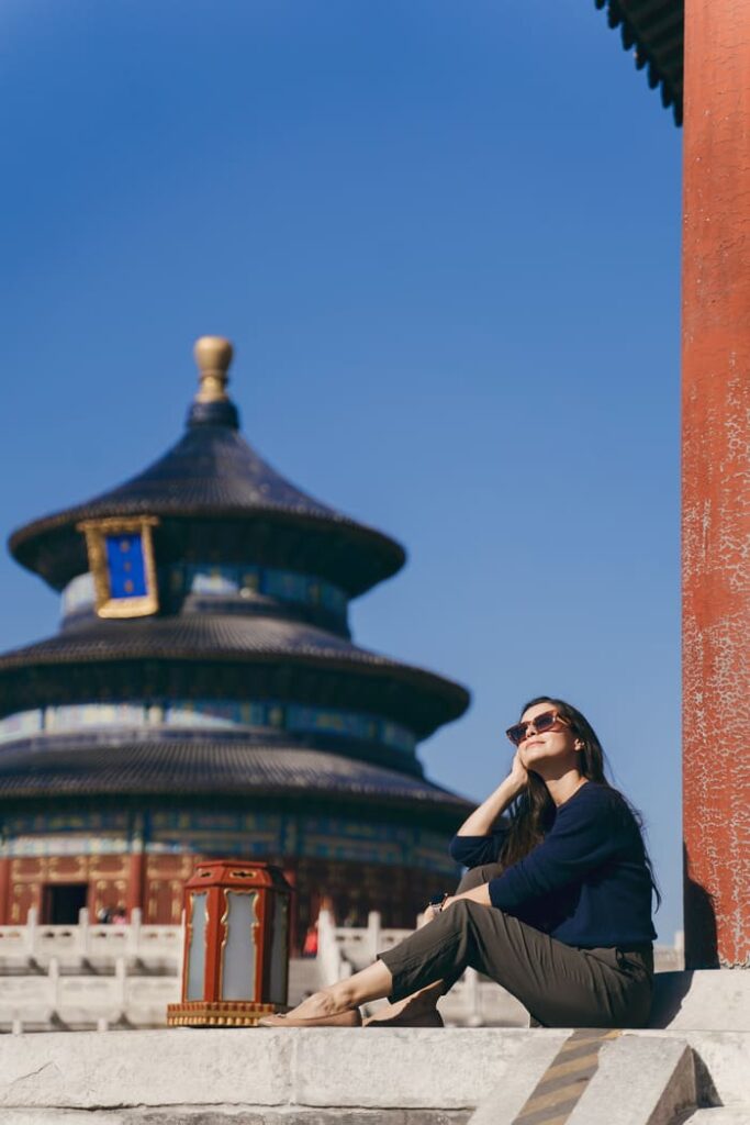 Mujer sentada frente al Templo del Cielo en Beijing durante un día soleado.
