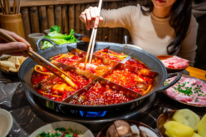 Personas disfrutando de un tradicional hot pot de Chongqing, uno de los platillos más emblemáticos de la gastronomía de China.