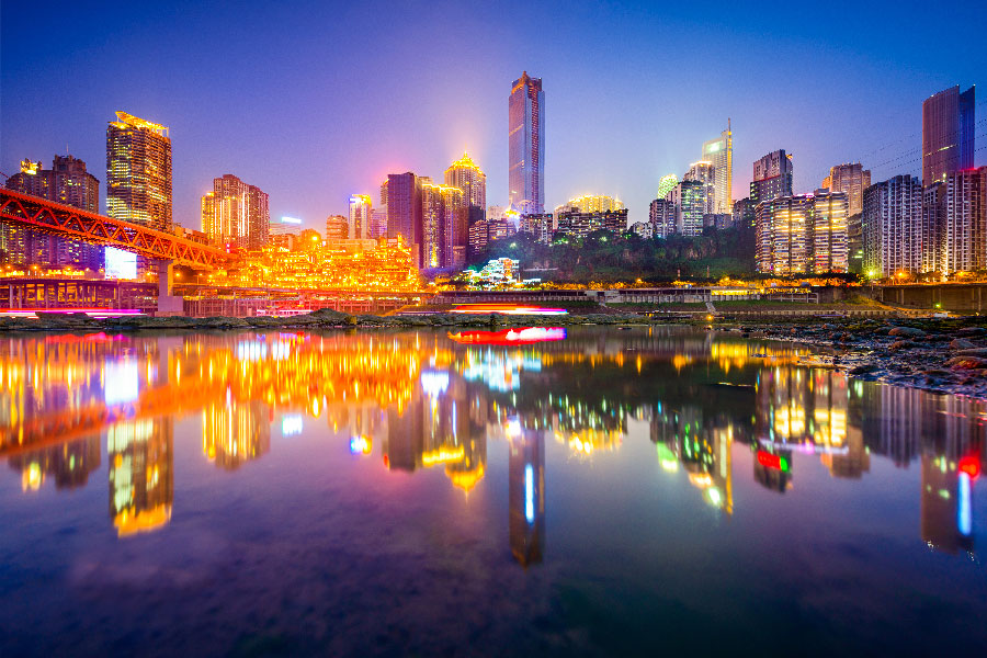 Vista nocturna del skyline de Chongqing, China, con rascacielos iluminados y reflejos sobre el río Yangtsé.