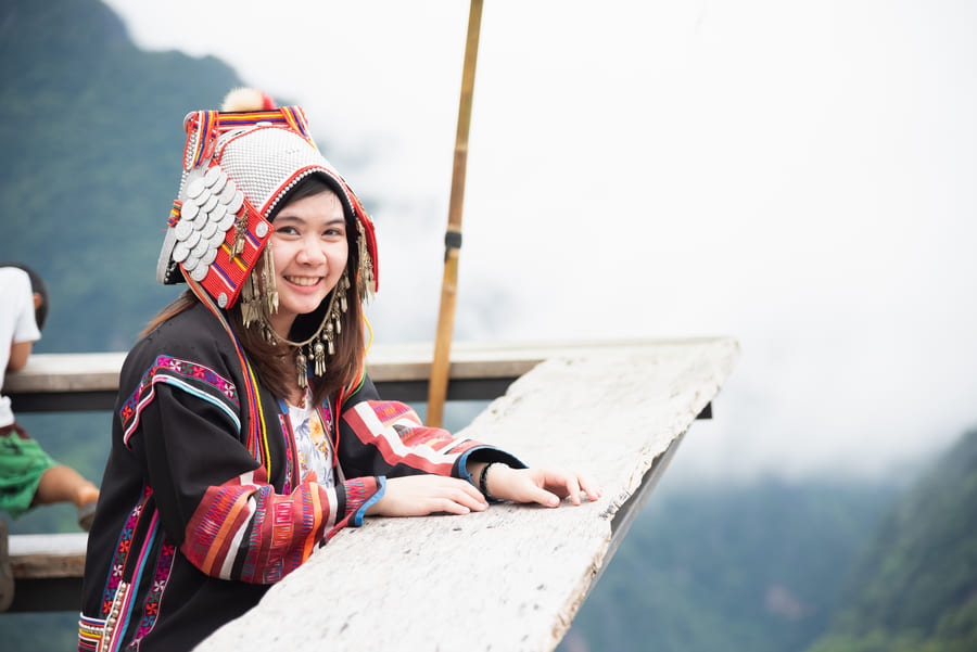 Experiencia cultural en Yunnan, China, donde una viajera posa con un traje tradicional de una comunidad étnica local.