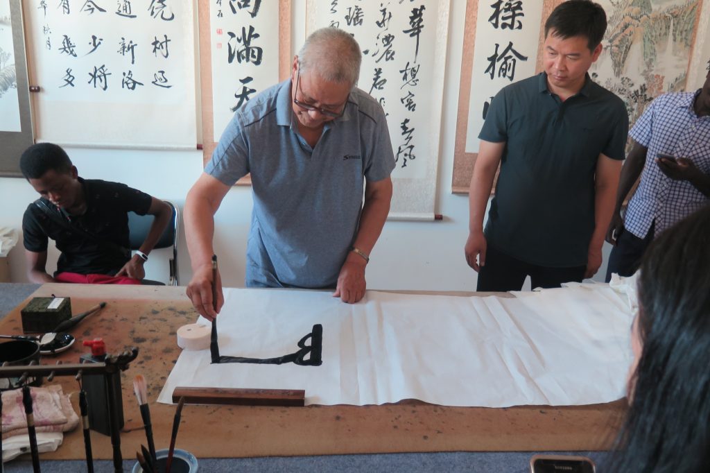 Clase de caligrafía china tradicional con un maestro enseñando técnicas de escritura con pincel, una experiencia cultural inmersiva para descubrir el arte, la historia y las tradiciones durante un viaje por China.