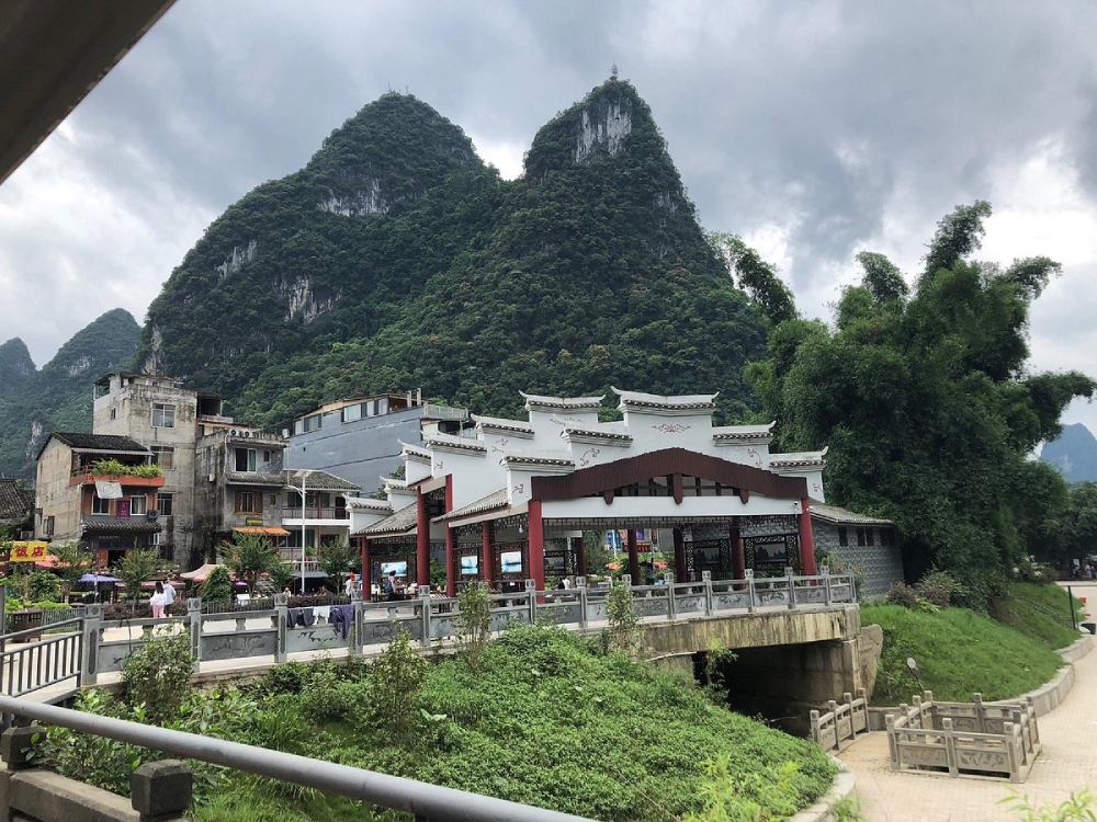 Arquitectura tradicional del pueblo de Xingping frente a imponentes montañas cubiertas de vegetación en la región de Guilin, China.